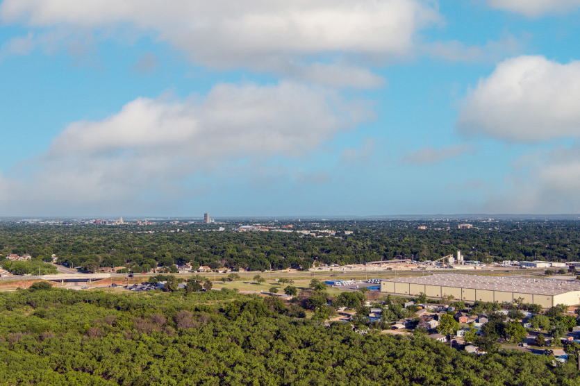 : Aerial establishing shot of Abilene Texas downtown cityscape with skyscrapers in the background traffic on the roads and a blue sky.