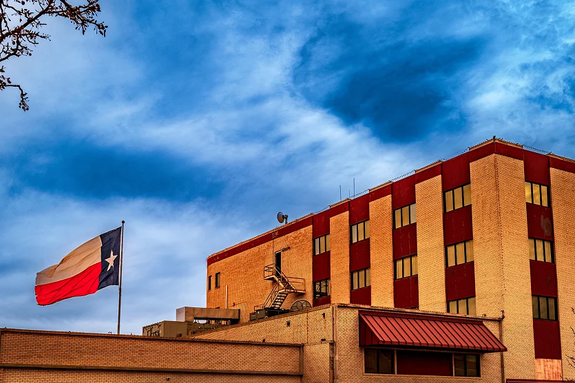Lone Star Texas State Flag waving in the wind over town building in Odessa - best home insurance in Texas.